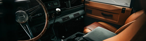 The Mark X Defender cabin: wood-rim wheel, black dash and tan leather with black door hardware